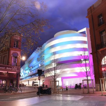 batiment éclairé la nuit avec un effet d'aurores boréales