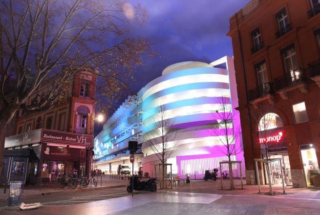 batiment éclairé la nuit avec un effet d'aurores boréales