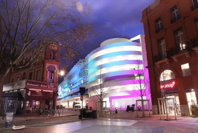 batiment éclairé la nuit avec un effet d'aurores boréales