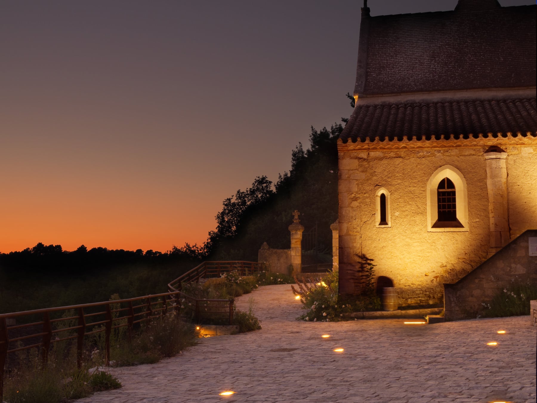coucher de soleil a bonaguil avec chapelle éclairée en premier plan