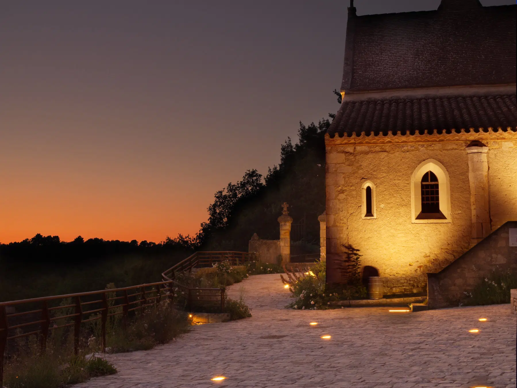 coucher de soleil a bonaguil avec chapelle éclairée en premier plan