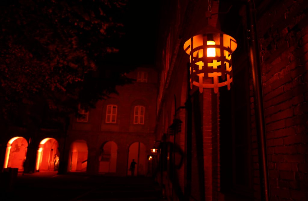 lanterne médiévale dans une cours en brique éclairée en rouge