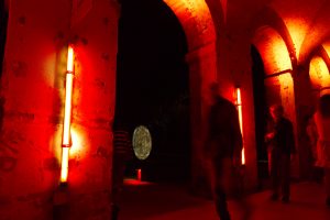 personnes sous arches éclairés en rouge avec néons