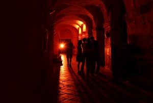 personnes déambulant dans un passage couvert avec voutes éclairé en rouge